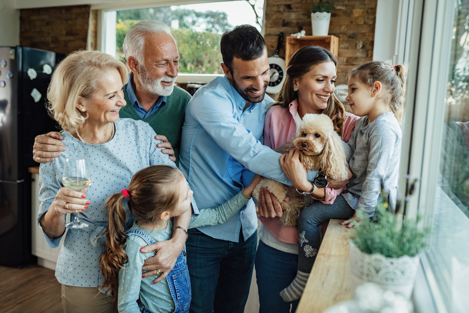 Familie in drei Generationen mit Hund auf dem Arm stehend in der Küche