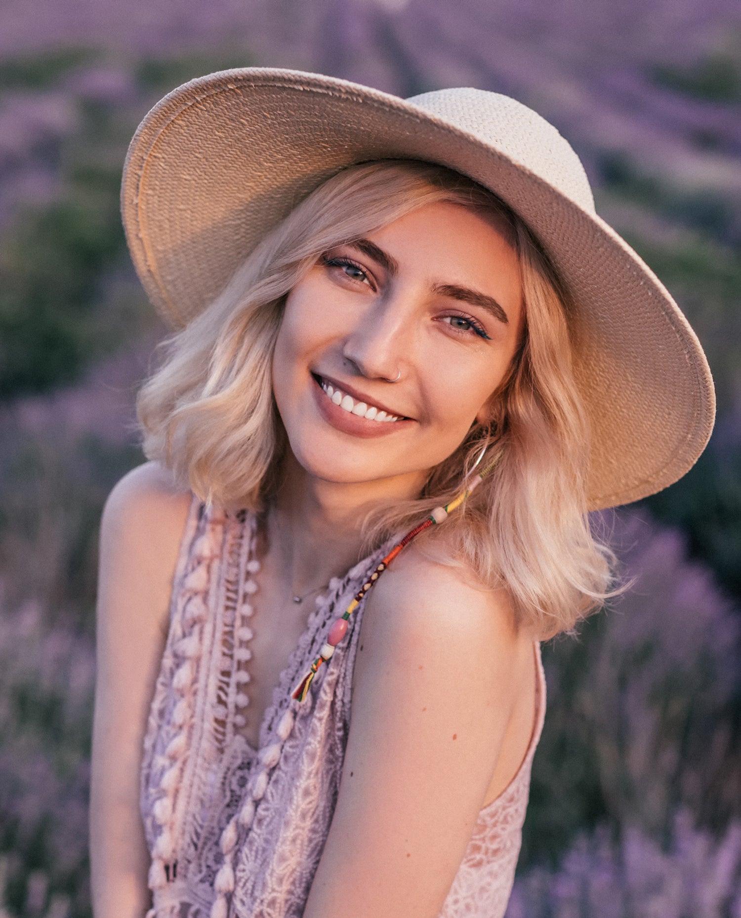 Blonde Frau mit großem Hut vor Lavendel-Feld